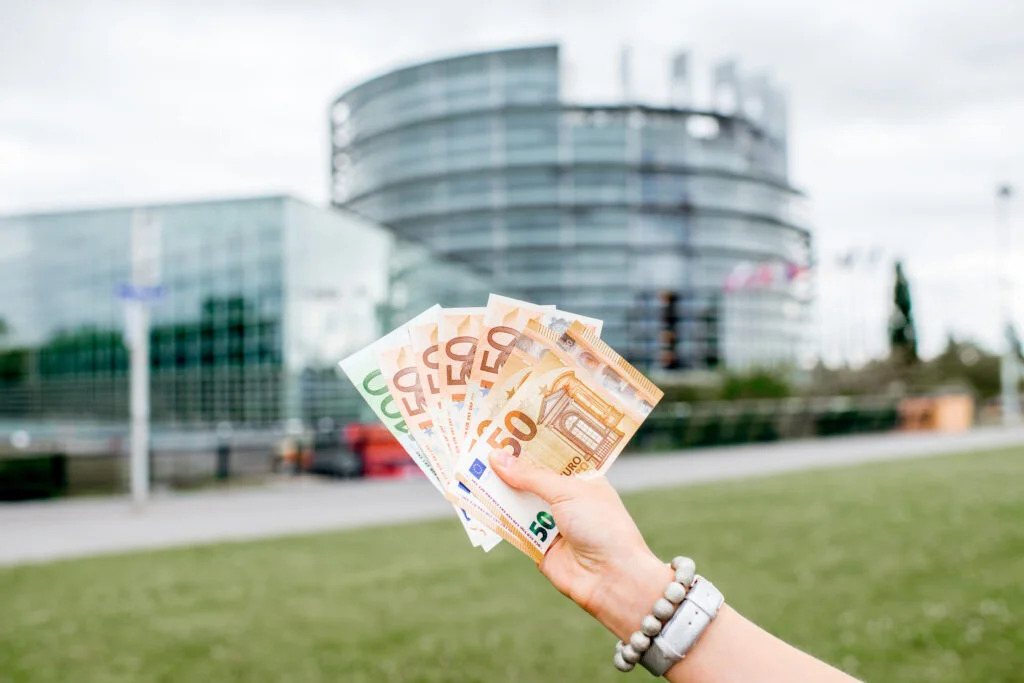 euroscheine in einer frauenhand vor einem gebäude