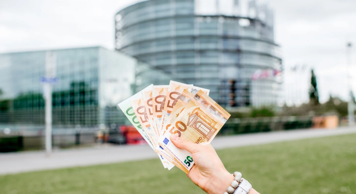 euroscheine in einer frauenhand vor einem gebäude