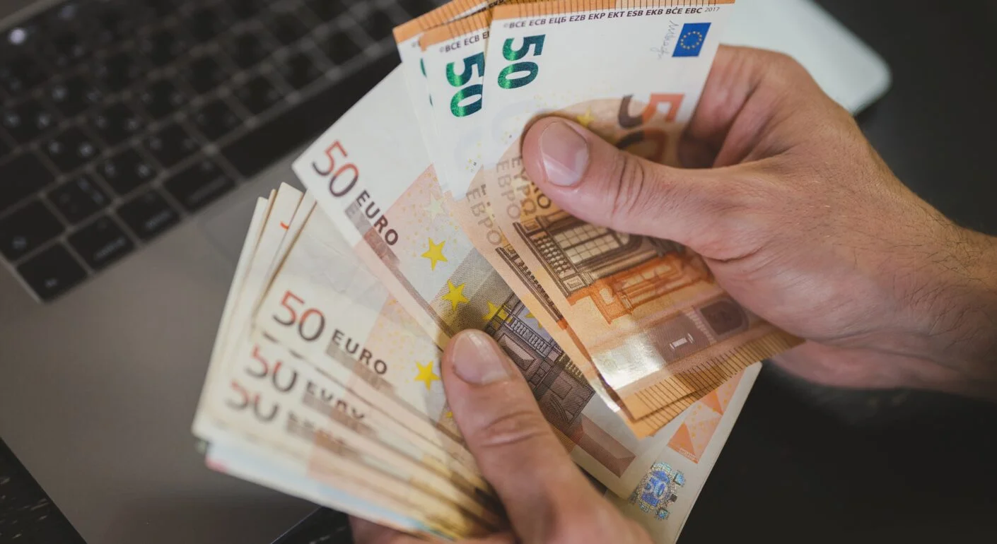 Mehrere 50€ Scheine vor einem Laptop